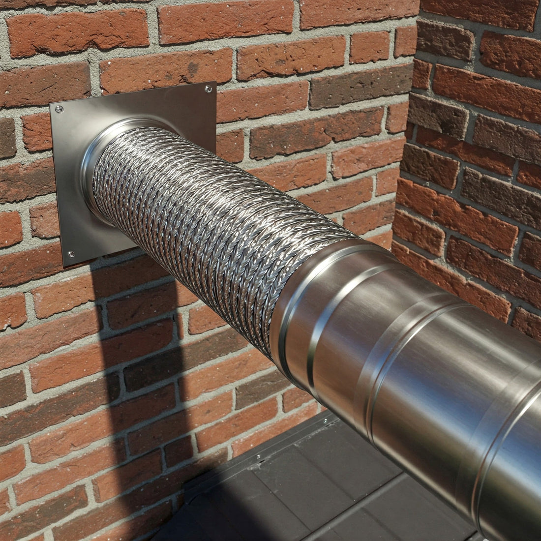 A close-up photograph of a high-quality stainless steel chimney liner, showcasing its smooth, reflective surface and durable construction. The liner is installed within a brick chimney, demonstrating its seamless integration and professional installation.